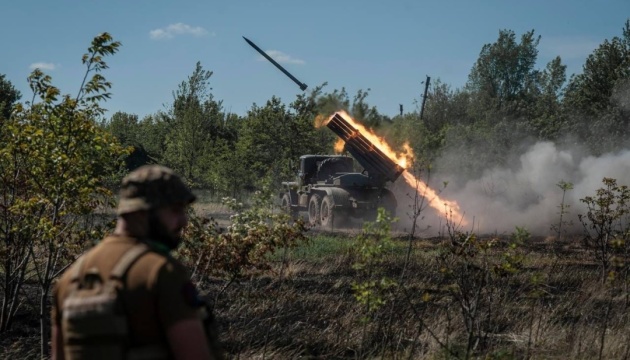 Military truck fires a large rocket in a rural field, flames and smoke trailing from the launcher while a soldier watches in the foreground. Military truck fires a large rocket in a rural field, flames and smoke trailing from the launcher while a soldier watches in the foreground.