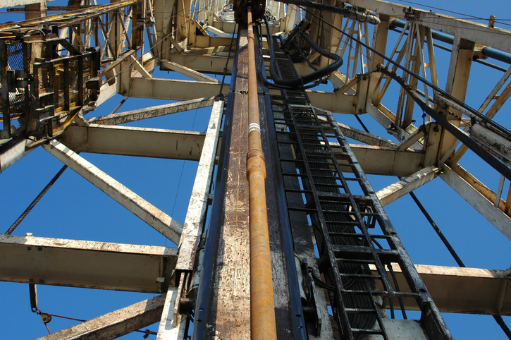 Upward view of a drilling rig showing dril pipe during drilling operation.